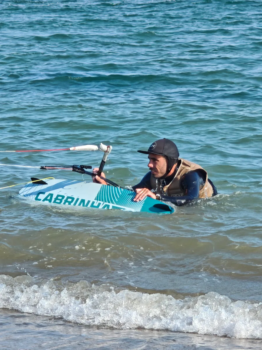 Kitesurfista recuperando la tabla en la orilla durante el waterstart