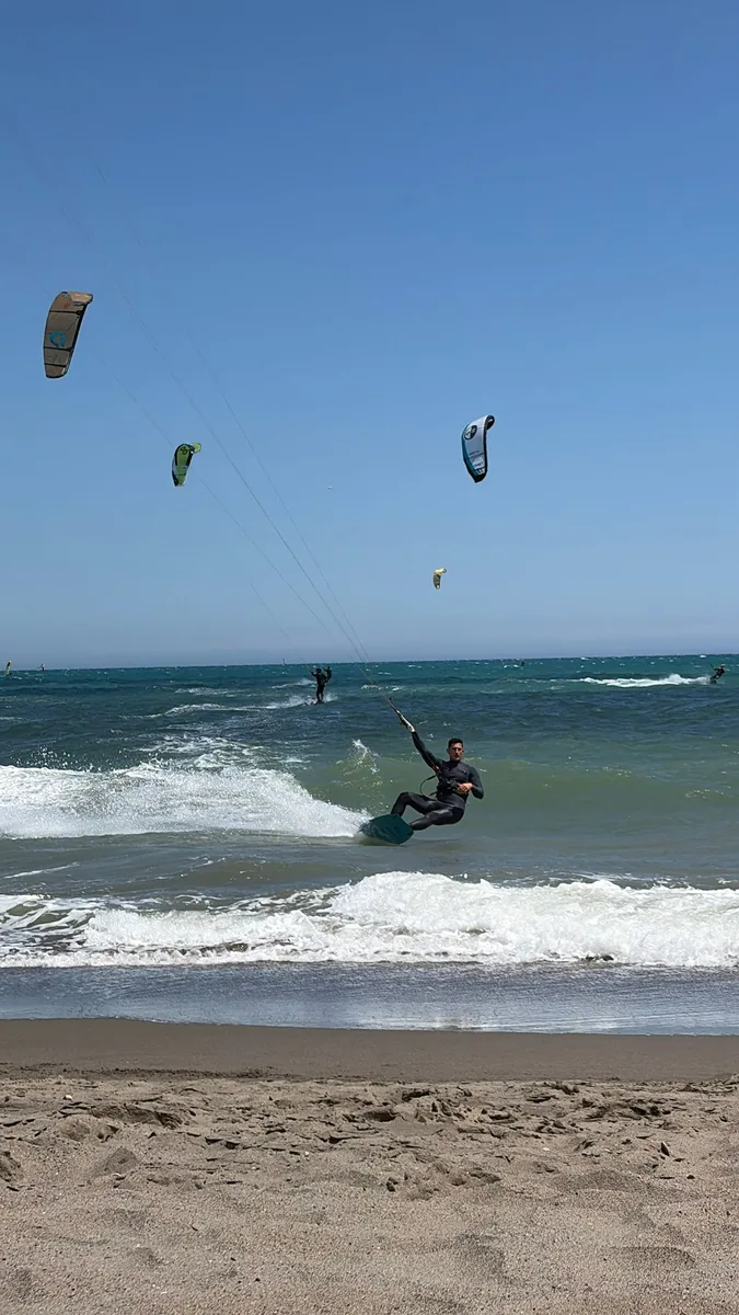 Kitesurf en la playa con varias cometas en el cielo